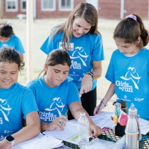 Girls on the Run junior coach is happily asking question to the program participants outdoors